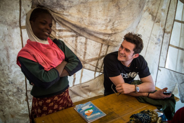 UNICEF Goodwill Ambassador Orlando Bloom (right) smiles as he listens to twelve-year-old Aicha Gabtchami, a fifth grade student, speak at a temporary learning space at a camp for internally displaced people in Ngagam, near Diffa, Niger, Friday 17 February 2017. Aicha, who was displaced from Barwa, Niger near Lake Chad, came to Ngagam camp with her mother and grandmother by foot. The family were forced to flee after being threatened by Boko Haram members, who killed other people around them as they fled. Her uncle was killed while in the bush. Aicha’s father, who had already left Barwa, was also killed by Boko Haram insurgents. Attending classes at the school makes Aicha feel better, “more comfortable” as she puts it. (CNW Group/UNICEF Canada)