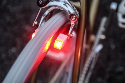 Magnic Microlight tail light prototypes mounted on a bicycle with caliper brakes: The current for the rotatable headlight is generated by eddy current induction, separated via an air gap from the non-magnetic aluminium rim. Over time, the white generator part shifts outward by a mechanism in the black brake shoe housing to prevent rim contact as the red brake rubber wear progresses. Magnic Microlights can be used on almost all rim brakes and can be mounted on bicycles with disc brakes by a clamp + adapter replacing the brake rubber