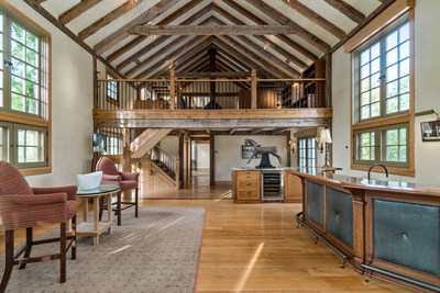 Interior living spaces of the barn include multiple areas for recreation and entertainment, such as the open-plan living room with wet bar (pictured here). The third-level recreation room offers a central, wood-burning fireplace and a large screen TV set in a handsome cabinet that swivels to allow viewing from multiple seating areas. NewJerseyLuxuryAuction.com.