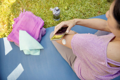 User wearing Abbott&rsquo;s world-leading FreeStyle Libre system and scanning with a smartphone.