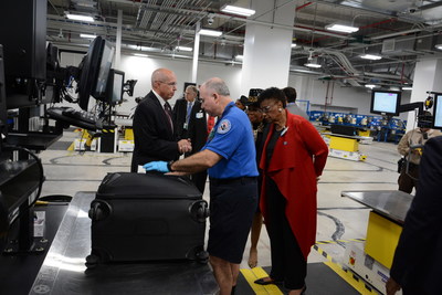 TSA Federal Security Director Daniel Ronan demonstrates the bag rescreening process for County Commissioner Barbara Jordan and Representative Wilson.