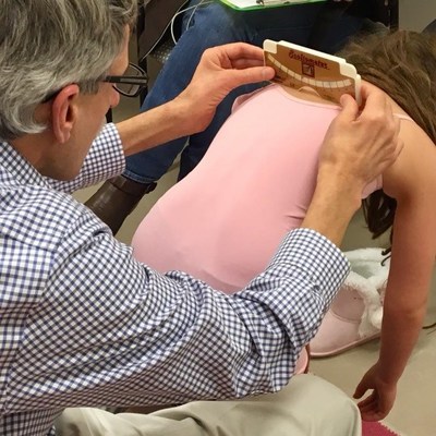 Luke Stikeleather of the National Scoliosis Center performing a scoliosis screening on a child. Luke Stikeleather of the National Scoliosis Center performing a scoliosis screening on a child.