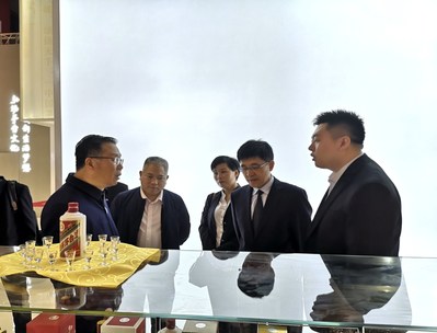 Li Baofang, président de Moutai (1er à gauche) et Li Jingren, directeur général de Moutai (2e à droite), visitent le kiosque d’exposition de Moutai et obtiennent des renseignements détaillés à propos des produits.