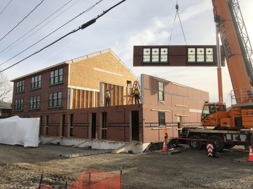 Cranes pick and place the prefab panels for Boathouse Landing in Ithaca, NY. The 16-unit development was completed in October 2019.