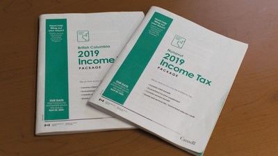 Photo of two paper 2019 income tax packages, with the package for Nunavut resting on top of the package for British Columbia. (CNW Group/Canada Revenue Agency)