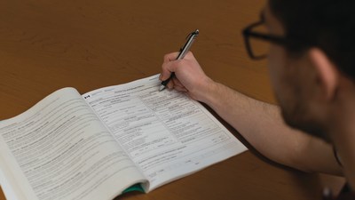 Photo of a man who is in the process of filling out his paper income tax package with a pen. (CNW Group/Canada Revenue Agency)