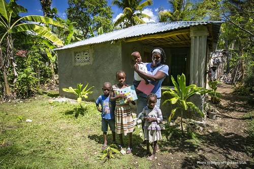 A Fonkoze-empowered mother and her children in front of her modest home in Haiti's Central Plateau