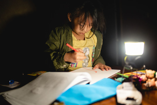 Girl draws by light of her new solar lamp.