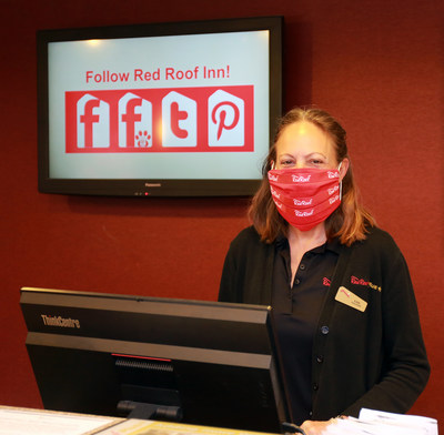 Red Roof front desk representative, Lisa Rowland, greets guests with a smile beneath her cloth face covering, following CDC guidelines and Red Roof RediClean enhanced cleaning protocols.