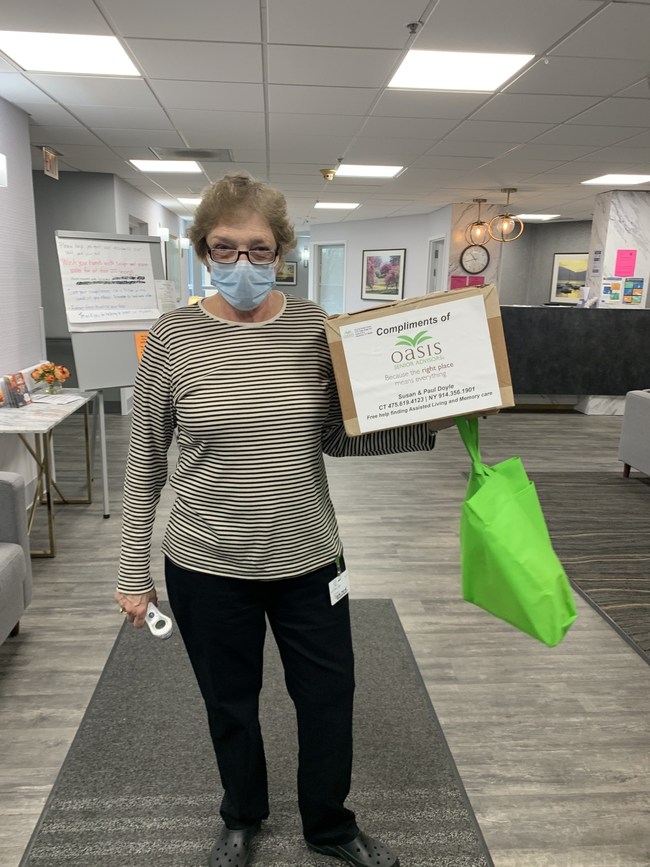 Healthcare worker in Connecticut with box of face shields donated Oasis Senior Advisors
