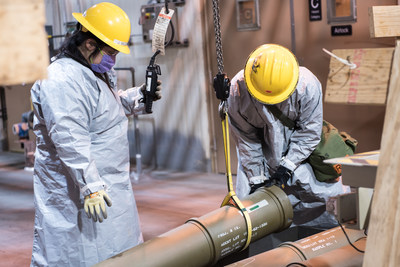 Two operators place one of the last overpacked 8-inch projectiles containing the GB nerve agent into a tray to begin the destruction process at the Blue Grass Chemical Agent-Destruction Pilot Plant in Kentucky. The final 8-inch projectile of GB was destroyed on May 11, marking the complete elimination of an entire type of chemical weapon.