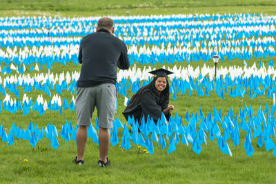 LCCC graduate Damarilys Hernandez, who earned her associate of arts degree, in the center of the flags as her father snaps a picture on her graduation day.