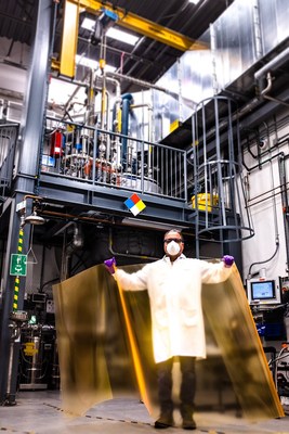 In the foreground, Nanosys Facilities and Equipment Manager presents a sheet of UbiGro® greenhouse film that uses fluorescent quantum dots to help plants get more from the sun. Behind him stands an over 2,000 L quantum dot production reactor.