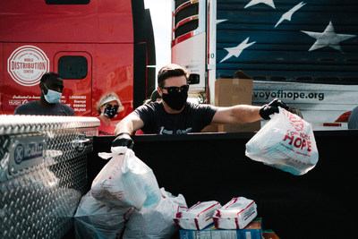 A volunteer packs meals and supplies into the back of a guest's truck as part of Convoy of Hope's "Beyond 10 Million Meals" initiative.