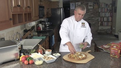 American Flatbread owner, Brad Sterl accessorizing a homemade pizza.