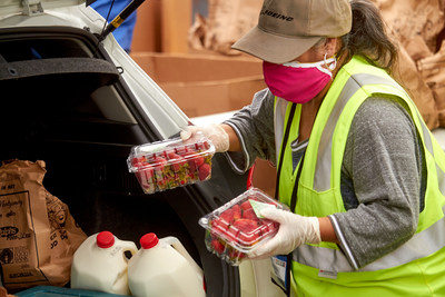 A volunteer loads a drive-thru food distribution participant's car with emergency food from the OC Food Bank.