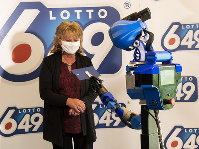 Guylaine Desjardins, la gagnante, et SARA, le robot conu, coordonn et contrl par le club tudiant Walking Machine de l'TS (Groupe CNW/Loto-Qubec)