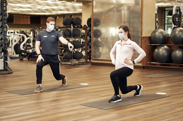 Picture of a personal trainer and woman exercising while they're wearing masks 