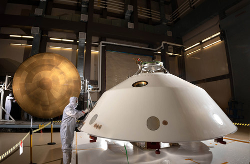 Lockheed Martin engineers work on the construction of the aeroshell for the Mars 2020 mission. The cone-shaped back shell and orange heat shield will protect the Perseverance rover on its way to the surface of Mars.