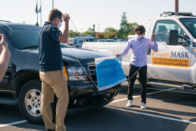 Mac Macleod, CEO of Carvertise, with the help of New Castle County Executive Matt Meyer, affixes a mask on a New Castle County vehicle at their August 5 launch event.