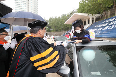 A 2019 graduate who couldnâ€™t have a traditional celebration because of the ongoing COVID-19 pandemic is receiving her diploma in car during the drive-in ceremony held at Hongik Universityâ€™ Seoul campus, which is supported by KT Corp., on August 21.