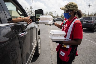September 2, 2020. Michele Grady of the American Red Cross hands out meals at a drive-thru distribution point for families affected by Hurricane Laura in Lake Charles, LA. Contributions from Annual Disaster Giving Program (ADGP) and Disaster Responder Program members ensure the American Red Cross is prepared to provide help and hope to people affected by disasters like storms and countless other crises.  Photo by Scott Dalton/American Red Cross.