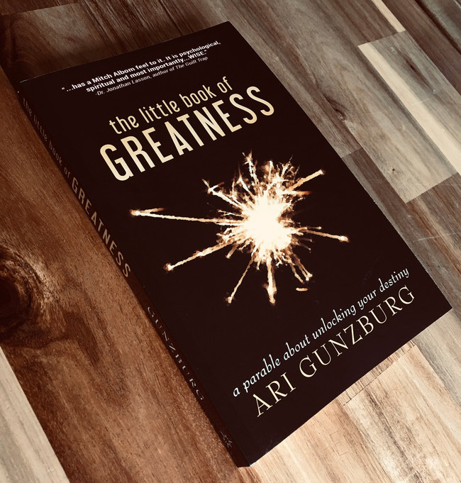 The Little Book Of Greatness on wood background