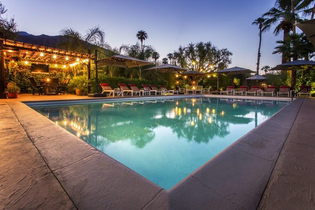 Evening photo of Desert Riviera Hotel's heated pool and guest barbecue area on the left.