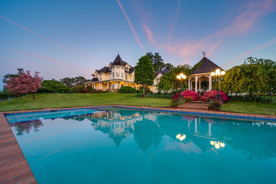 The residence and pool in the evening glow. Also pictured is a lovely, poolside gazebo surrounded by fresh flowers and plantings. The property also boasts a large, outdoor living area that includes a custom-built summer kitchen with fire pit, pizza oven and bar with seating for 12 guests. Learn more at OregonLuxuryAuction.com.