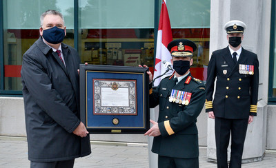Major-General Richard Goodyear, Senior Canadian Armed Forces Logistician (right), formally presents Doug Ettinger, President and CEO, Canada Post, (left) with a Royal Canadian Logistics Branch commendation, to commemorate 15 years of the cost-free mail program for deployed personnel and to recognize Canada Post’s routine support of Canadian Forces Postal Service. Also featured: Captain Navy Francis Turcotte, Royal Canadian Logistics Service Advisor/Integrator (far right). Credit: Denis Drever (CNW Group/Canada Post)