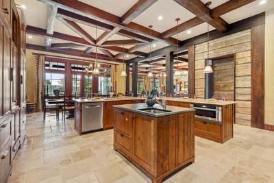 As seen here in the kitchen, the residence uses a blend of warm woods and natural stone throughout the interiors, creating a look of relaxed and rustic luxury. Woods used in the exposed beams date 300 years. The indoor kitchen is complemented by an outdoor grill and bar area (not pictured), perfect for a barbecue with friends after playing 18 holes. Visit GeorgiaLuxuryAuction.com.