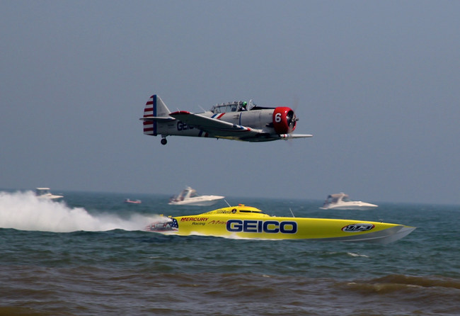 The 47-foot Miss GEICO Victory catamaran races one of the solo aircraft from the GEICO Skytypers Air Show Team.