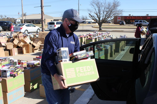Volunteers from Norman Regional Hospital load boxes of food and essentials into the cars of Oklahoma families.