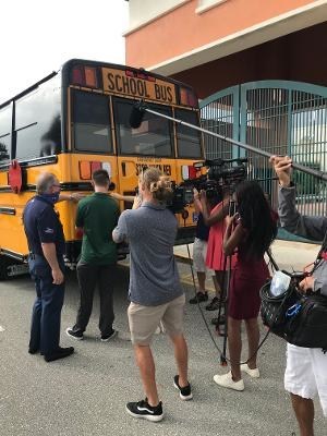 Rob Thomson, Realtor at Waterfront Properties with Jupiter High School Students as they place tag on the new bus.