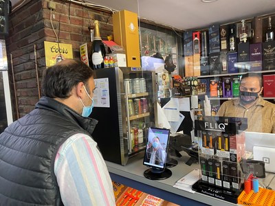 Sid Dilawri, owner of Modern Liquors store in Washington DC, uses MaskCheck in “active mode” to see if his mask is worn properly, while a store clerk looks on.