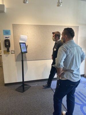 RealNetworks’ Mike deVoss (in dark sweater) installs MaskCheck kiosk in “active mode” at the South (staff) entrance of The Bush School in Seattle, and shows Facilities Director Michael Miller how it works.