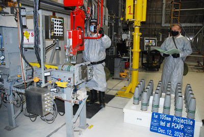 Workers at the Pueblo Chemical Agent-Destruction Pilot Plant load the first 105mm projectile into equipment where it will be taken apart and destroyed.