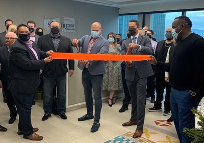 CEO Jim Pate and COO Ryan Marier cut the red ribbon at the grand opening of Secure One Capital's new executive suite surrounded by members of their management and sales teams. Walter A. Mar, VP of People and Culture, and Basilio Castillo, VP of Sales are holding the ribbon.