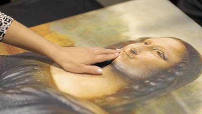 A visitor explores the surface of a tactile image of 'The Mona Lisa'.