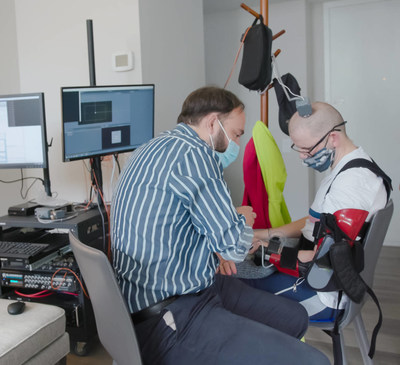 Mijail Serruya, MD, PhD (left) and patient (right) working on the Cortimo clinical trial to test using brain implants to control a motorized brace that fits over the patient's stroke-affected arm, at Thomas Jefferson University.
