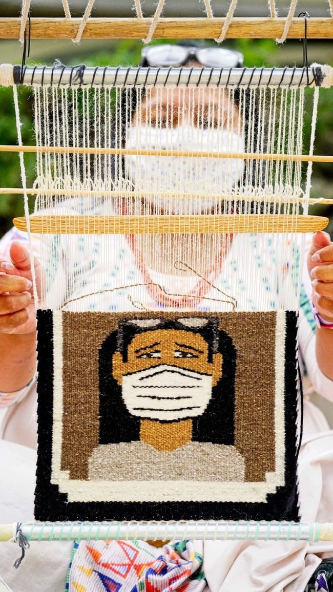 Pamela Brown, a recipient of BlessingWay's COVID relief, is at her loom weaving a pictorial Toadlena/Two Grey Hills rug of a Navajo wearing a face mask. Photo by Stephen Henderson & Metamorphosis The Art of Living