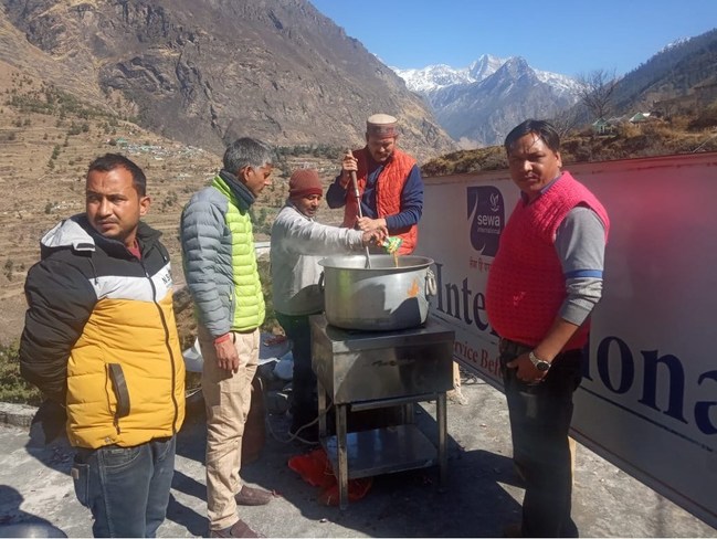 Sewa volunteers preparing meals near a relief site