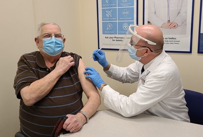 Shoppers Drug Mart Associate Owner Tony Alm gives the store's first COVID-19 vaccine to Eugene Bochon in Edmonton, AB. (CNW Group/Loblaw Companies Limited)