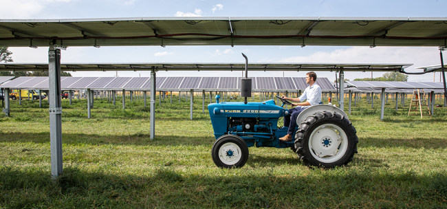 Byron Kominek, owner of Jack's Solar Garden, riding his family's tractor through their solar power system. Photo courtesy of Werner Slocum, National Renewable Energy Laboratory