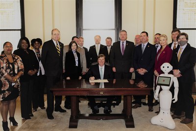 Lt. Gov. Delbert Hosemann, other state legislators, C Spire executives and Pepper, the telecom and technology services firms' humanoid robot, flank Gov. Tate Reeves as he signs into law a bill that paves the way for computer science curriculum in all Mississippi K-12 public school classrooms.
