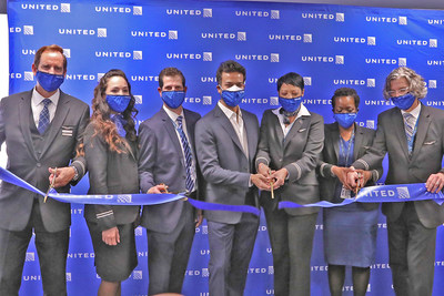 Ribbon cutting of first United flight from JFK to SFO with David Kinzelman and Ankit Gupta surrounded by flight crew and employees.