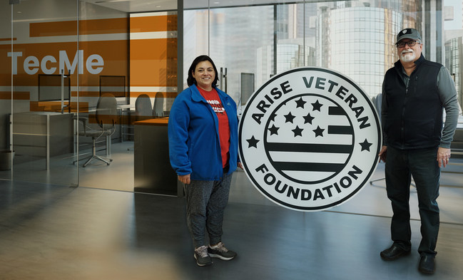 Depicts Chairman Dr. Kendal Brune (right) next to Arise Veteran Foundation logo at TecMe branded office.