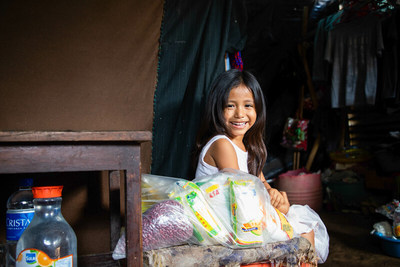 A young girl from El Salvador sits in her home with a food pack from Compassion's church partner.