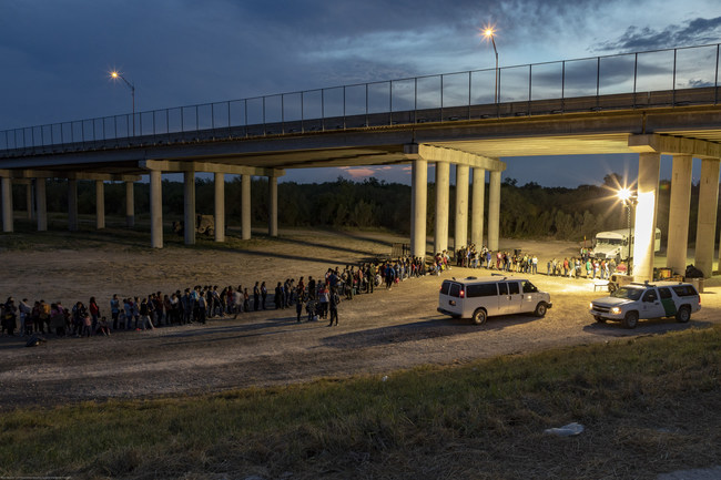 Migrants seen lining up to be detained by Customs and Border Patrol (U.S. Customs And Border Control / Flickr)