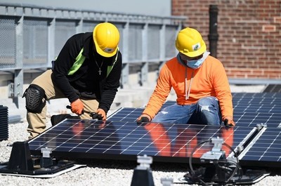 Two New York City Housing Authority residents who have gotten apprenticeships as solar installers under a Con Edison project. The 12 apprentices are placing panels on three NYCHA developments. The power will be available to low- and moderate-income customers on a discounted basis.
